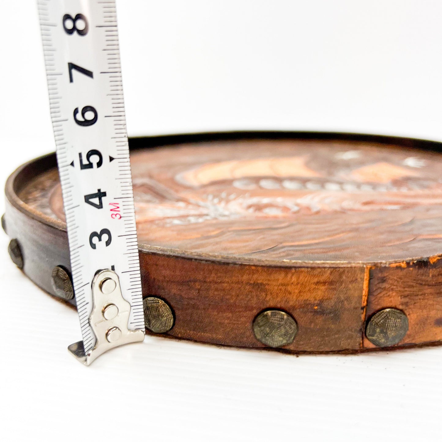 Vintage brown leather round hanging artwork with ship artwork.
