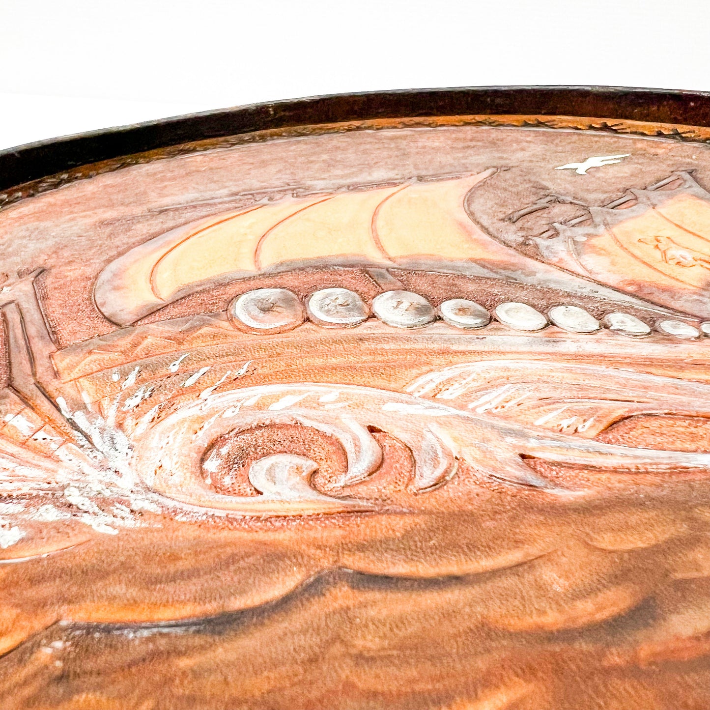 Vintage brown leather round hanging artwork with ship artwork.