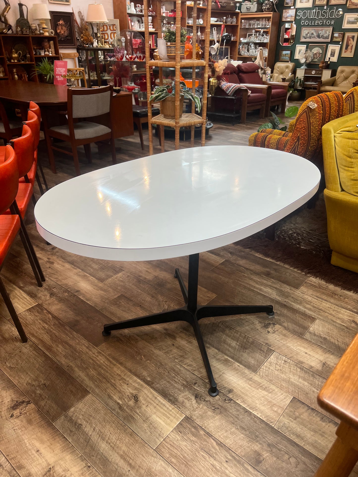 White oval dining table with black steel pedestal base