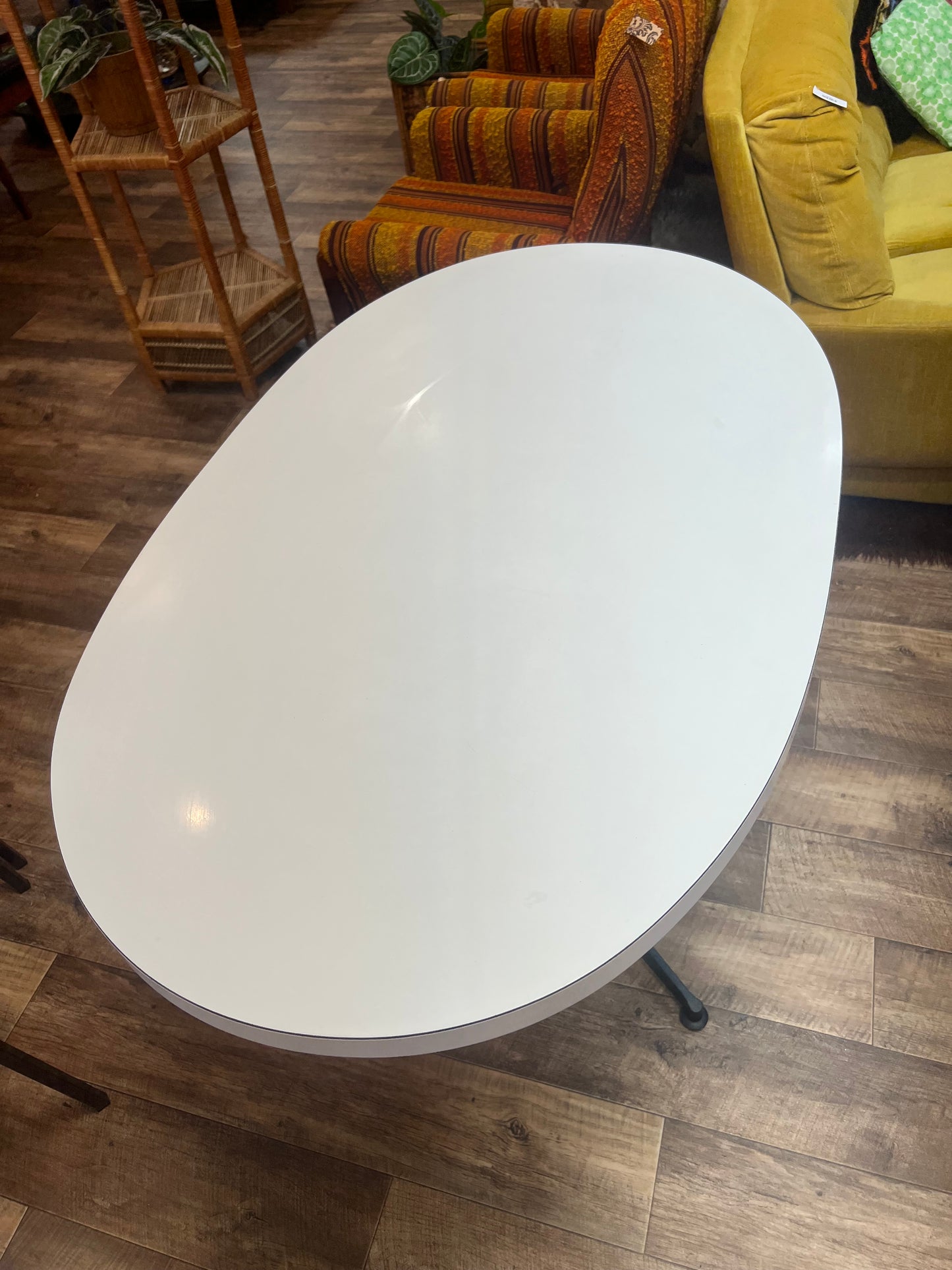 White oval dining table with black steel pedestal base
