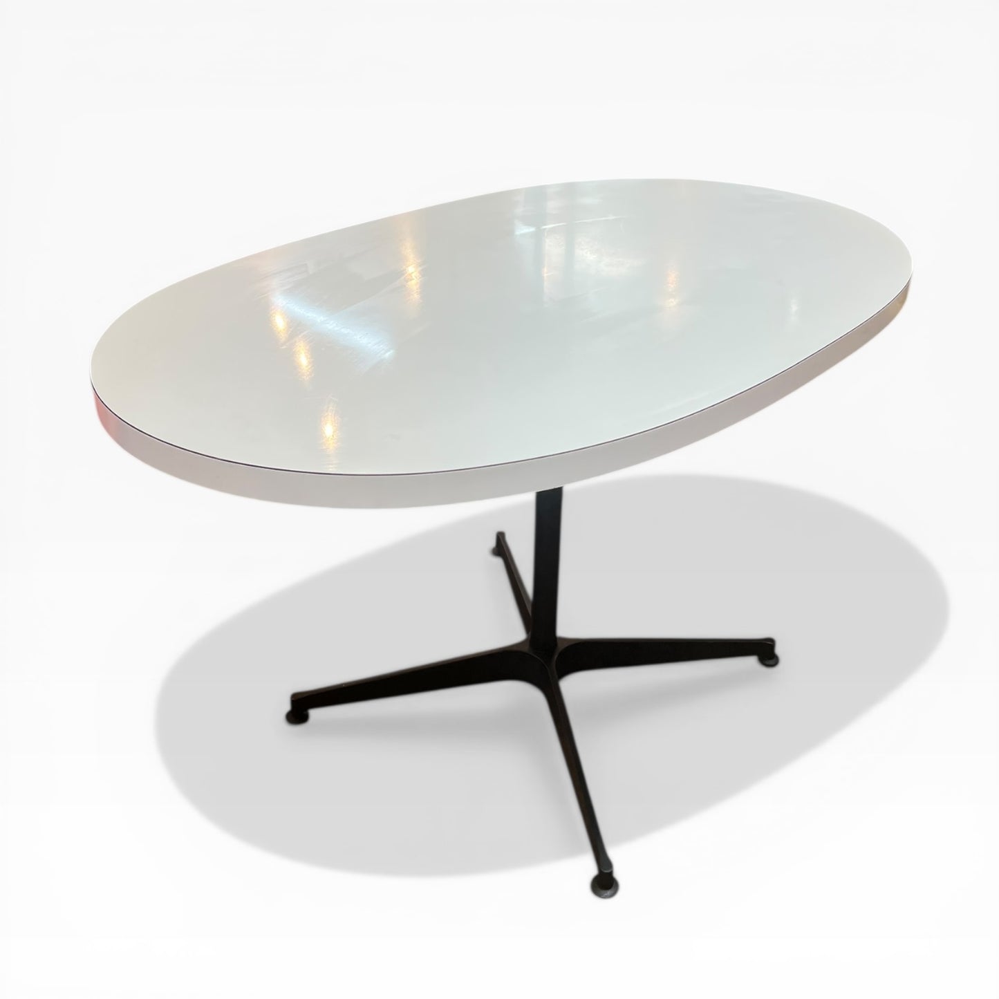 White oval dining table with black steel pedestal base