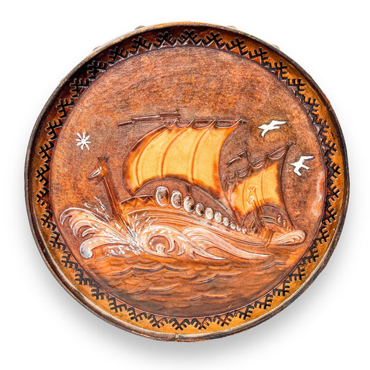 Vintage brown leather round hanging artwork with ship artwork.