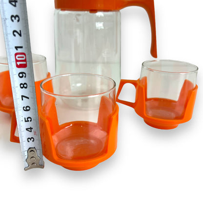 JAJ Pyrex Clear glass jug & 3 cups with orange plastic handles and lid.