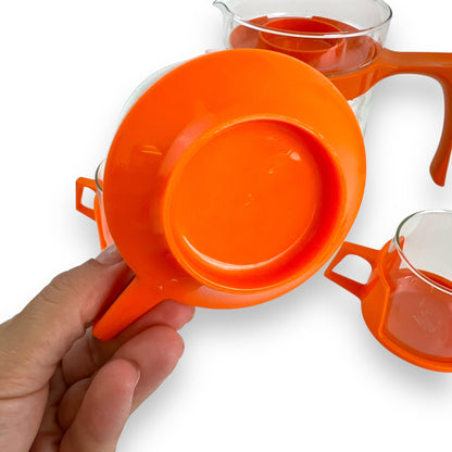 JAJ Pyrex Clear glass jug & 3 cups with orange plastic handles and lid.